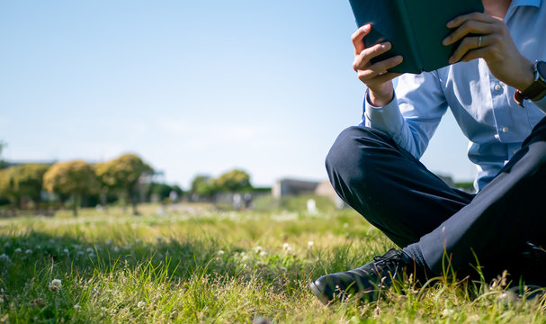 草原で本を読むビジネスマン - Powered by Adobe