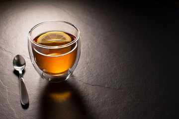 Cup of tea with lemon on black granite background