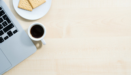 Laptop, coffee cup and cookies on wooden table, top view, home office area, copy space