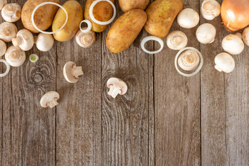 Fototapeta na wymiar Mushrooms, potatoes and onion rings with garlic on a wooden background. Template for the text.