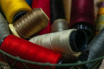 Various colors of thread rolls sits in wooden basket 