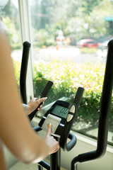 Close-up vertical photo. A female hand changes the settings of the Control Panel on the stepper...
