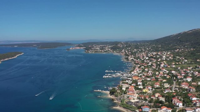 Mediterranean settlement Barbat, with natural habour and boats, surrounded with turquoise sea, City of Rab in background, Island of Rab, Croatia - Aerial Panoramic View
