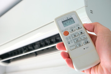 Man's hand using remote control open The air conditioner is cooled to 25 degrees Celsius in his bedroom. Health concepts and energy savings