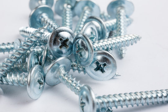 Steel screws randomly lie on a white background. Necessary parts for the assembly of furniture. Repair topic