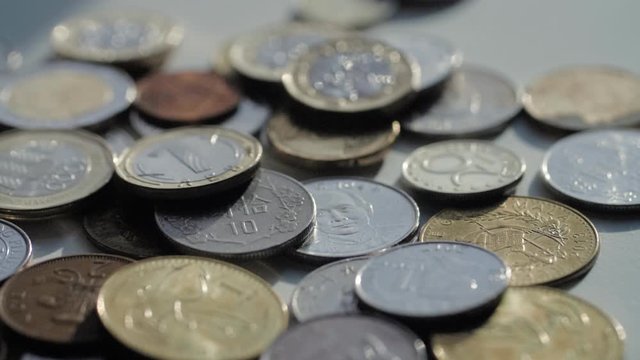 Coins falling on top of a pile of various coins currencies in slow motion (Useful for finance exchange concepts).