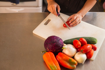 detail of woman hands cutting vegetables in her kitchen - young woman cooking vegan food - salad, healthy food