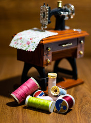 Fototapeta premium Mini sewing machine with multi-colored threads around it