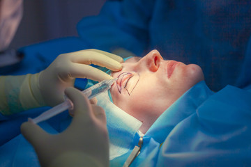 Naklejka premium Surgeon inserts an injection into the upper eyelid of the patient before performing the eyelid lift operation. Blepharoplasty