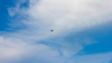 A plane flying through a cloudy blue sky
