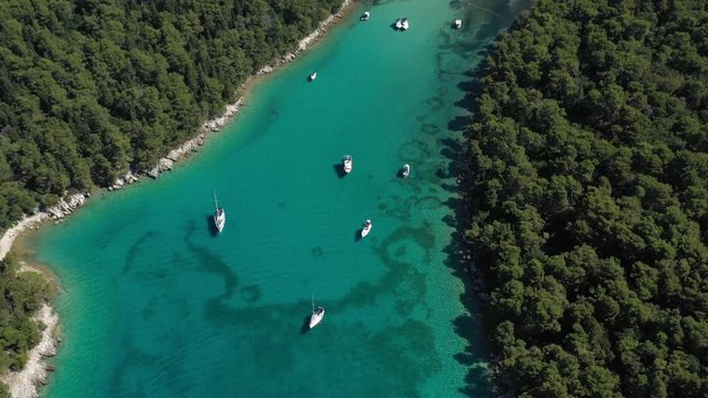Beautiful Turquoise Cove with mediterranean sand beach, anchored Sailboats and tourists swimming, Island of Rab in Croatia - Aerial Top Down View