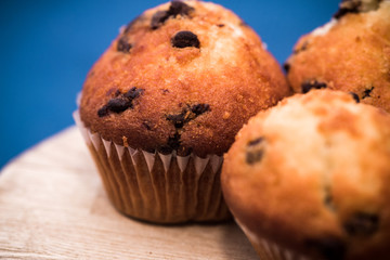 cupcakes with chocolate on wooden table and blue background