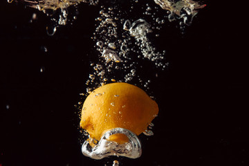 Fresh lemon falling into water. Isolated on black background