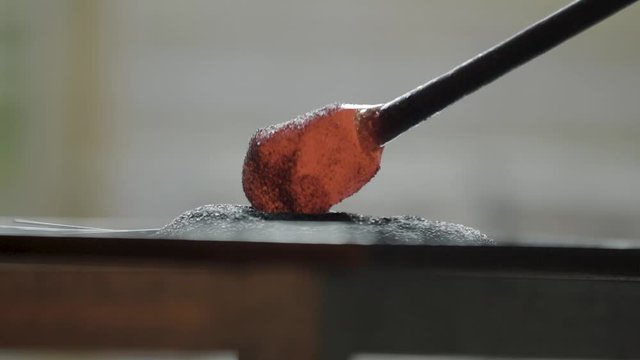 Rolling molten glass in powder to apply patterns and color to blown glass
