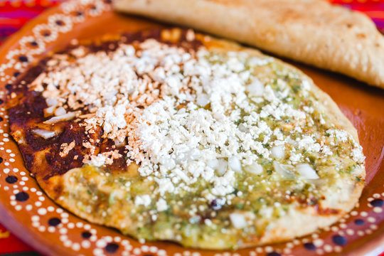 Mexican sopes with grated cheese and green salsa, mexican food spicy in mexico