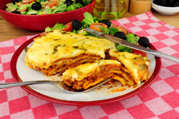 Slow cooked beef and pork ragu lasagne meal with fresh salad and olives