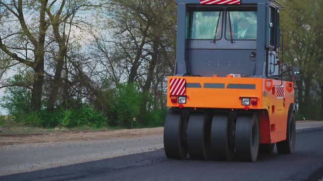 Roller machines make new asphalt roads. The asphalt paver squeezes hot asphalt.