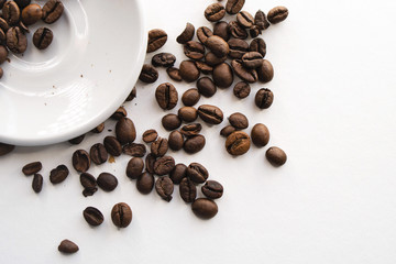 Coffee beans in white saucer and on white background. Top view.