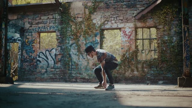 Man dancing in abandoned building while wind blows dust away