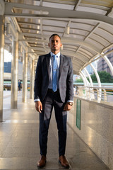 Full body shot of young handsome African businessman wearing suit in the city