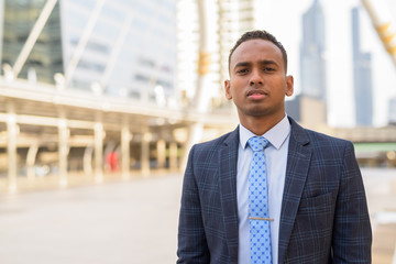 Young handsome African businessman wearing suit in the city