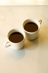 cups of coffees on white marble table in morning light
