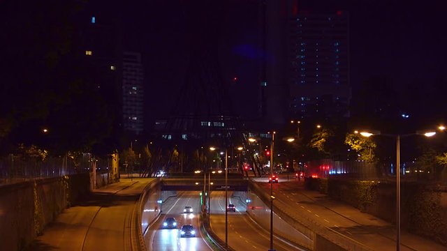 Driving cars in Munich, bavaria. A timelapse of the night traffic in central munich with many cars driving by, view from a bridge with famous architecture in the dark background.