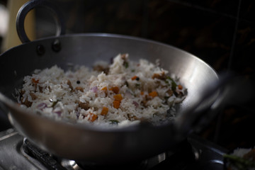 Steamed rice with vegetables being cooked in a large pot in an Indian kitchen. Indian food and cooking.