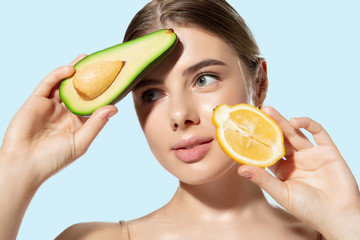 Close up of beautiful young woman with fresh lemon and avocado on white background. Concept of cosmetics, makeup, natural and eco treatment, skin care. Shiny and healthy skin, fashion, healthcare.