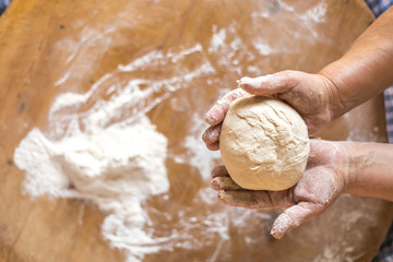 Female hands kneading dough on wooden table