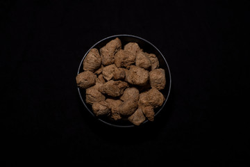 Top down image of a bowl of soya chunk in a dark copy space background. Food and product photography.