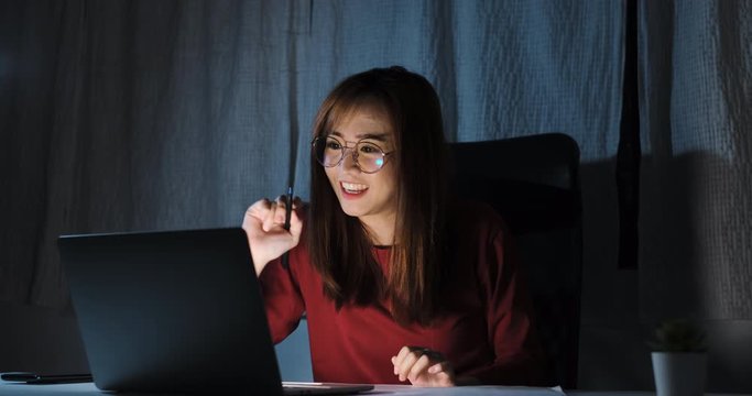 Asian Woman Video Conference User Interface At Night On Laptop Computer Online Remotely Working From Home Social Distancing Discussing With Internet Video Call Technology Quarantine Self Isolation.