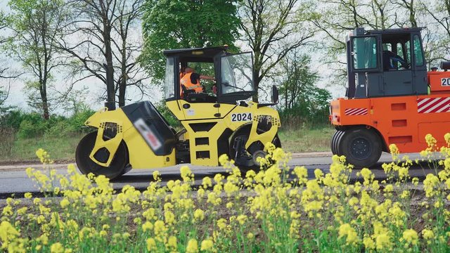 Roller machines make new asphalt roads. The asphalt paver squeezes hot asphalt.