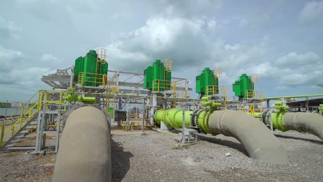 Industrial large-scale seawater pumping station with green heavy-duty pumps and massive pipelines. Cooling system for power plant or desalination facility in a coastal industrial area.