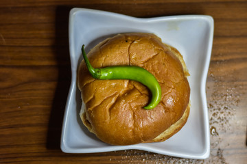 Mumbai most common and famous Vada pau bread and green sauce on a plate in dark background, Indian...
