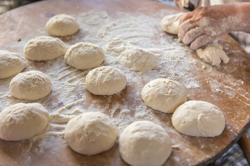 Female hands kneading dough on wooden table