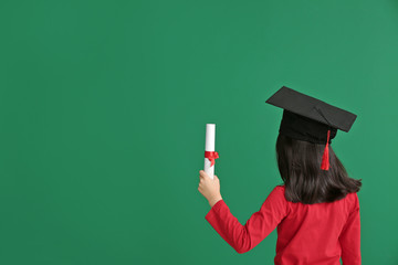 Little girl in graduation hat and with diploma on color background