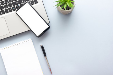 Blue desk office with laptop, smartphone and other work supplies with cup of coffee. Top view with copy space for input the text. Designer workspace on desk table essential elements on flat lay