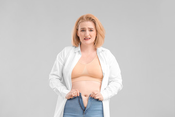 Troubled overweight woman on grey background