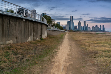 Tall skyscrapers of a modern, metropolitan cityscape tower over a beautiful, white, sandy beach on a warm, sunny day.