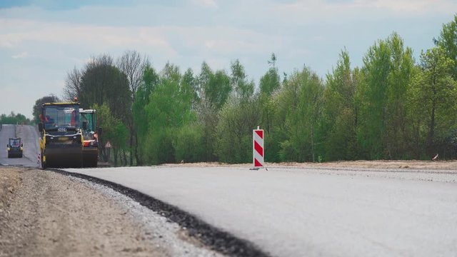 Roller machines make new asphalt roads. The asphalt paver squeezes hot asphalt.