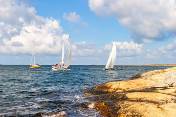 Seascape view with sailboats at a rocky coastline