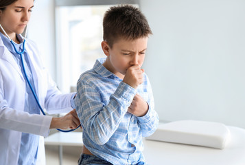 Ill coughing little boy visiting doctor in clinic