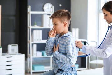 Ill coughing little boy visiting doctor in clinic