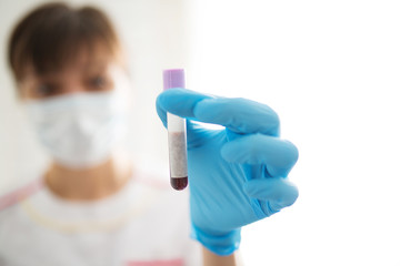 Female nurse holding test tube with blood sample with blank label