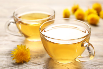 Cups of healthy dandelion tea on wooden background