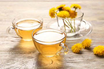 Cups of healthy dandelion tea on wooden background
