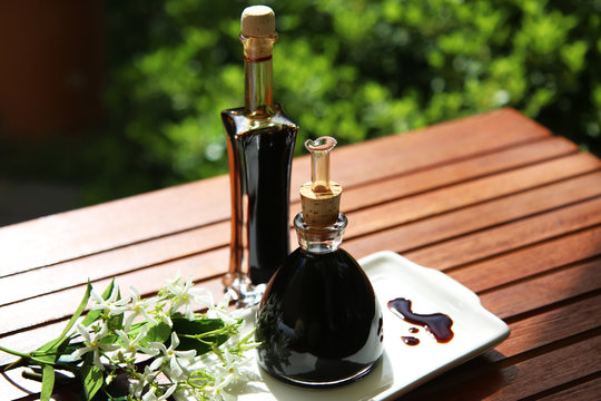 Bottiglie di aceto balsamico tipico di Modena, primo piano, su un tavolo in giardino