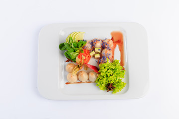 Sushi, danie kuchni japońskiej, podane na białym talerzu, dodatki warzywa i sałaty.