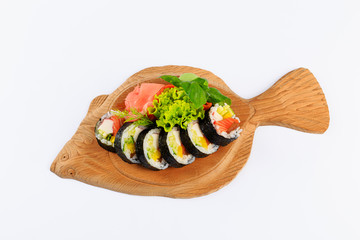 Rolki sushi na drewnianym talerzu w kształcie ryby.